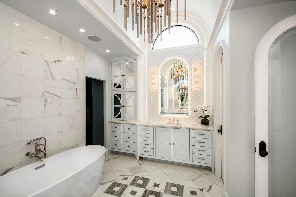 Пример оригинального дизайна: большая главная ванная комната в классическом стиле с отдельно стоящей ванной, белой плиткой, мраморной плиткой, белыми стенами, мраморным полом, врезной раковиной, разноцветным полом, белой столешницей, белыми фасадами, зеркалом с подсветкой и фасадами в стиле шейкер