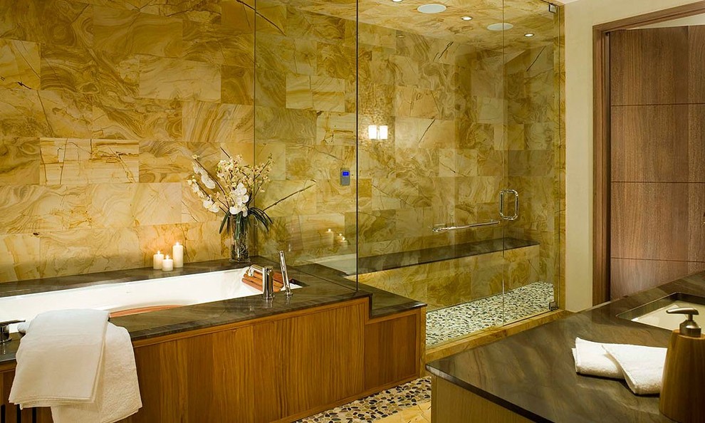 Modern inredning av ett stort en-suite badrum, med skåp i mellenmörkt trä, ett undermonterat badkar, en kantlös dusch, beige kakel, kakel i småsten, beige väggar, klinkergolv i småsten och ett undermonterad handfat