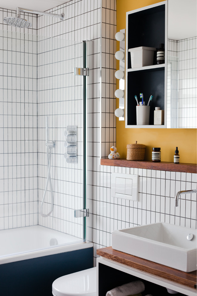 Design ideas for a midcentury family bathroom in London with a vessel sink, open cabinets, wooden worktops, a built-in bath, a shower/bath combination, white tiles and feature lighting.