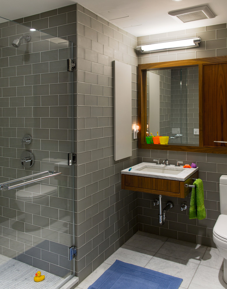 Immagine di una stanza da bagno design con piastrelle grigie, lavabo sospeso, ante in legno scuro, doccia alcova e piastrelle diamantate