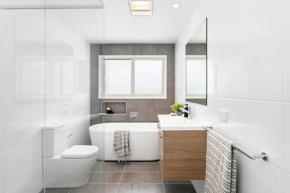 Idée de décoration pour une salle de bain principale design avec des portes de placard noires, une baignoire indépendante, WC séparés, un carrelage blanc, un lavabo intégré, un sol gris, une cabine de douche à porte battante et un plan de toilette blanc.