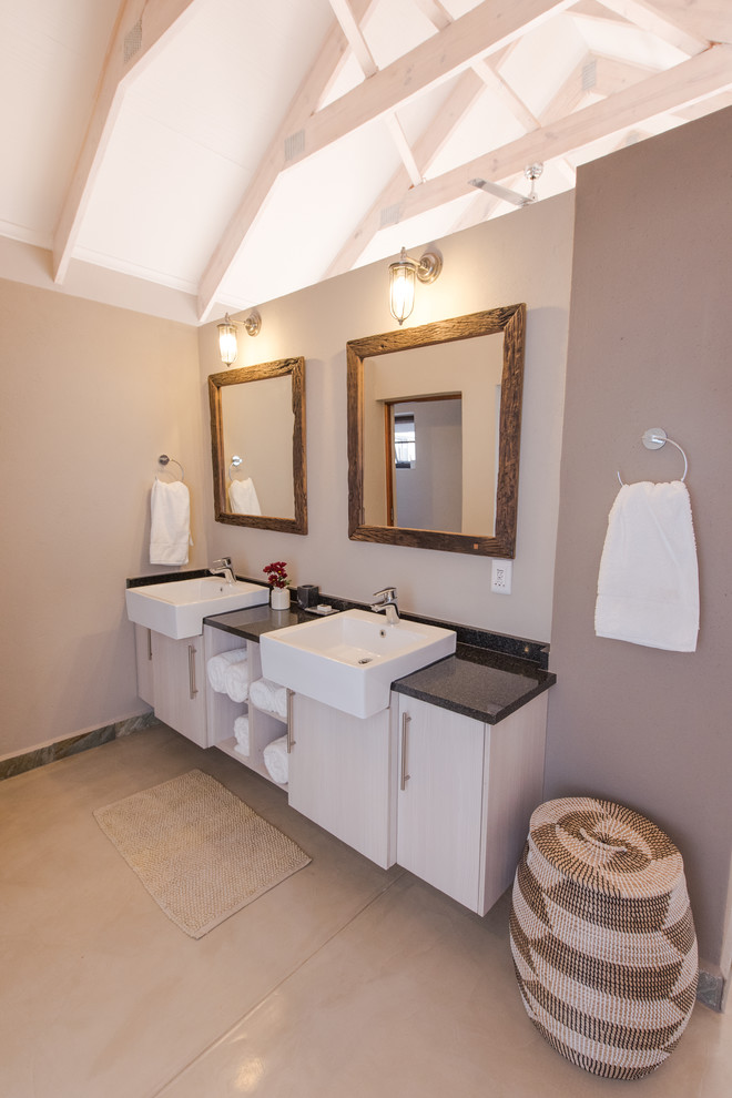 Medium sized rural bathroom in Other with flat-panel cabinets, white cabinets, a walk-in shower, a two-piece toilet, beige tiles, ceramic tiles, beige walls, concrete flooring, a built-in sink, granite worktops, beige floors, a sliding door and black worktops.
