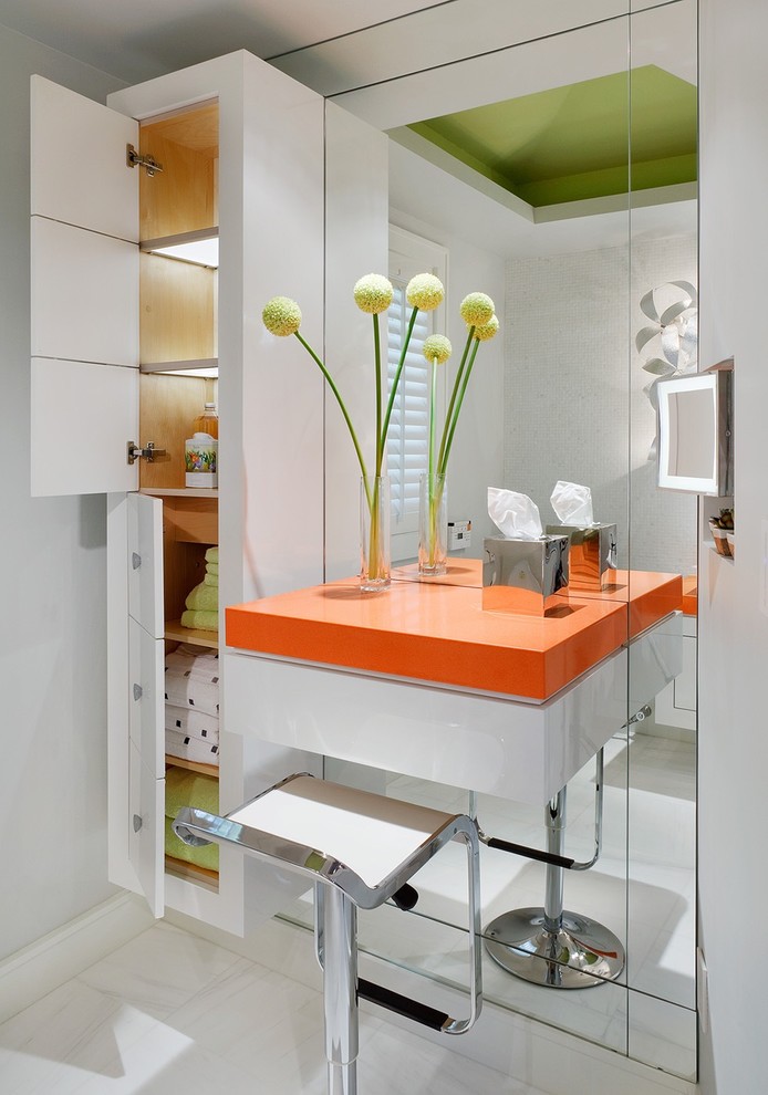 Cette image montre une salle de bain minimaliste avec un placard à porte plane, des portes de placard blanches, un carrelage blanc et un plan de toilette orange.