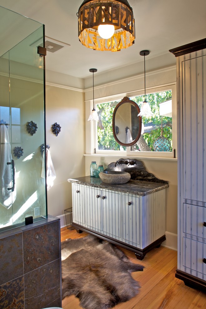 Mid-sized eclectic master multicolored tile and pebble tile medium tone wood floor corner shower photo in San Diego with beaded inset cabinets, distressed cabinets, a vessel sink, a two-piece toilet, beige walls and granite countertops
