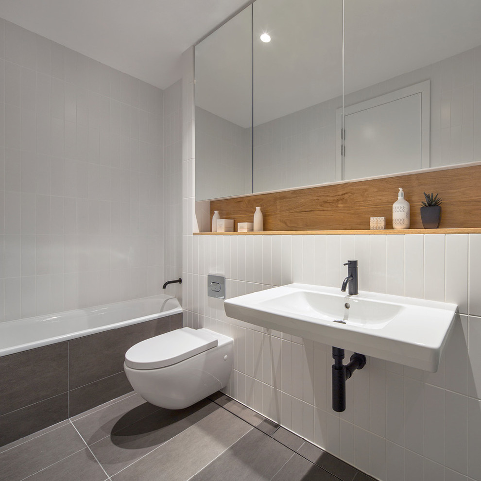 Exempel på ett modernt en-suite badrum, med ett badkar i en alkov, ett väggmonterat handfat, en vägghängd toalettstol, vit kakel, keramikplattor och klinkergolv i keramik