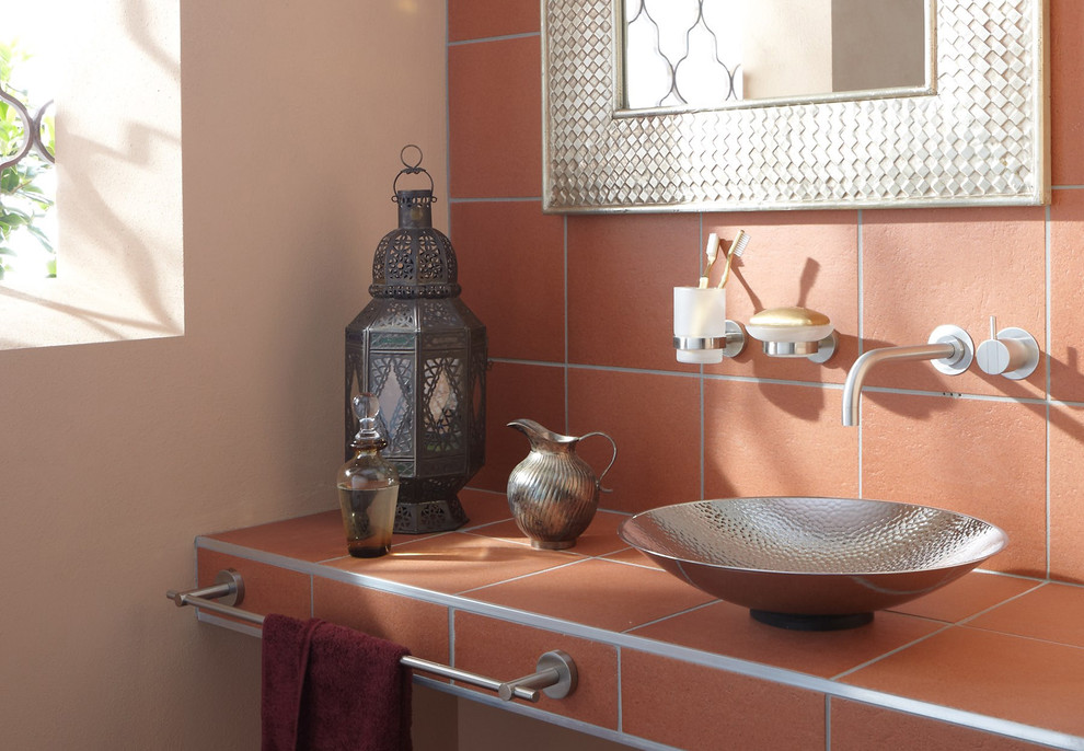 Immagine di una stanza da bagno eclettica di medie dimensioni con lavabo a bacinella, top piastrellato, piastrelle in terracotta e pareti beige