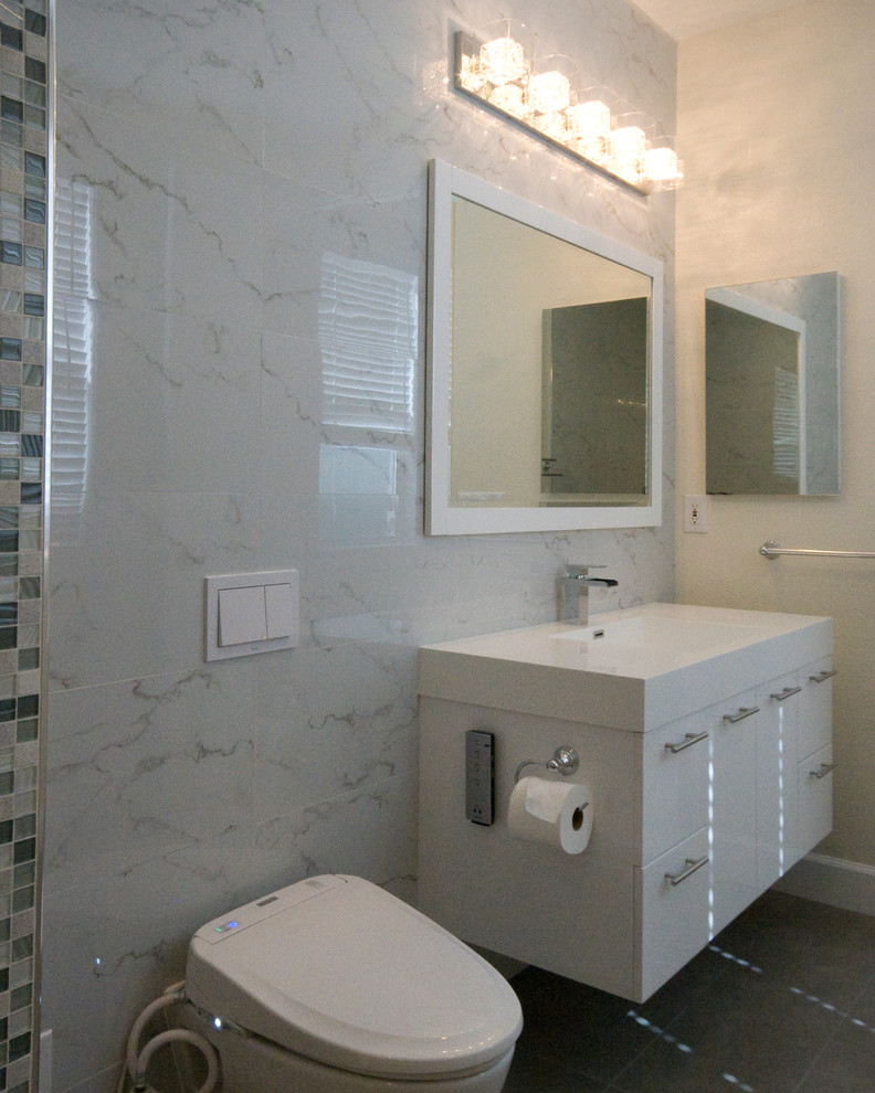 Réalisation d'une petite salle de bain bohème avec un lavabo intégré, un placard à porte plane, des portes de placard blanches, une baignoire indépendante, WC suspendus, un carrelage gris, un carrelage de pierre, un mur blanc et un sol en carrelage de céramique.