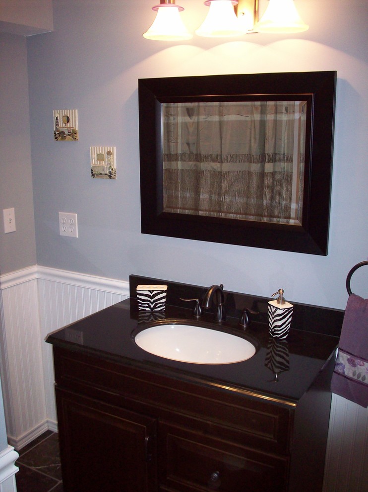Foto på ett badrum med dusch, med luckor med upphöjd panel, skåp i mörkt trä, marmorbänkskiva, en dusch i en alkov, en toalettstol med separat cisternkåpa, svart kakel, stenkakel, grå väggar och marmorgolv