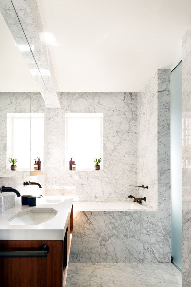 Exemple d'une salle de bain tendance en bois brun avec un placard à porte plane, une baignoire encastrée, un carrelage gris, un mur gris, un lavabo encastré, un plan de toilette blanc, meuble double vasque et meuble-lavabo suspendu.