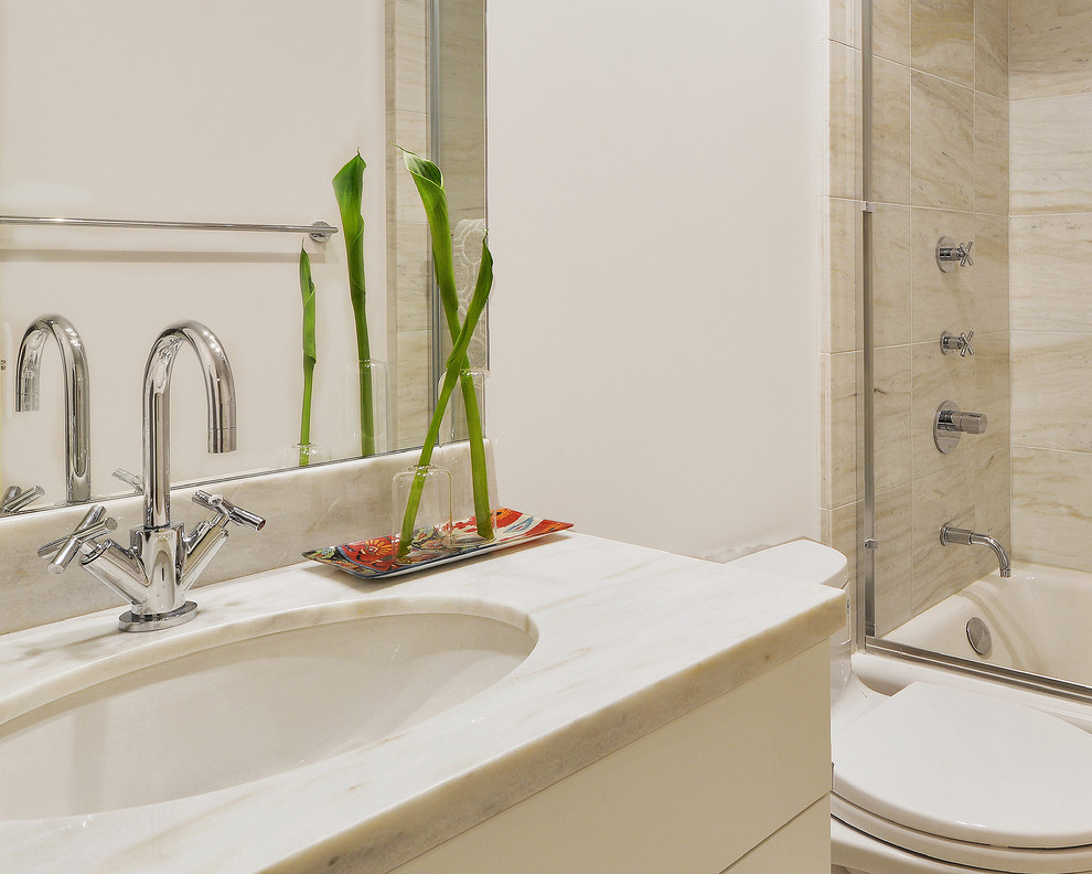 Foto på ett litet funkis vit badrum, med släta luckor, ett platsbyggt badkar, en dusch/badkar-kombination, vita väggar, kalkstensgolv, ett nedsänkt handfat, bänkskiva i kvarts, beiget golv, vita skåp, marmorkakel och dusch med skjutdörr