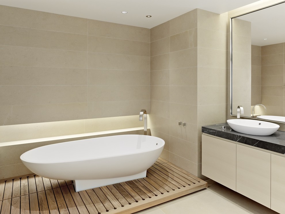 На фото: ванная комната в современном стиле с отдельно стоящей ванной, настольной раковиной и плиткой из известняка с
