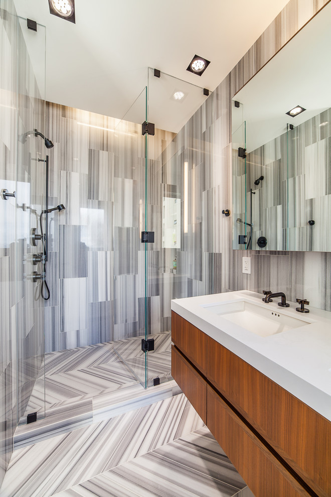 Свежая идея для дизайна: ванная комната в современном стиле с врезной раковиной, плоскими фасадами, фасадами цвета дерева среднего тона, душем в нише и серой плиткой - отличное фото интерьера