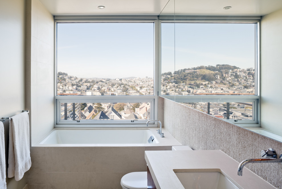 サンフランシスコにあるモダンスタイルのおしゃれな浴室 (アンダーカウンター洗面器、アルコーブ型浴槽、ベージュのタイル) の写真