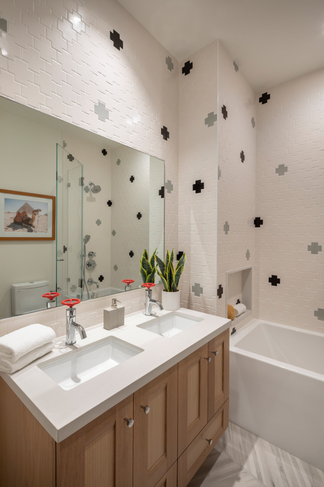 Пример оригинального дизайна: ванная комната среднего размера в стиле неоклассика (современная классика) с фасадами в стиле шейкер, ванной в нише, душем над ванной, унитазом-моноблоком, белой плиткой, керамической плиткой, полом из керамогранита, врезной раковиной, столешницей из искусственного кварца, душем с распашными дверями, белой столешницей, тумбой под две раковины, встроенной тумбой и душевой кабиной