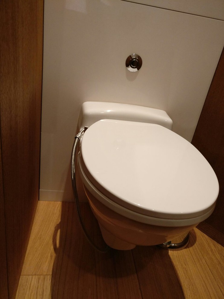 Immagine di una piccola stanza da bagno padronale design con WC sospeso, piastrelle bianche, lastra di pietra, pareti bianche, pavimento in bambù e pavimento marrone