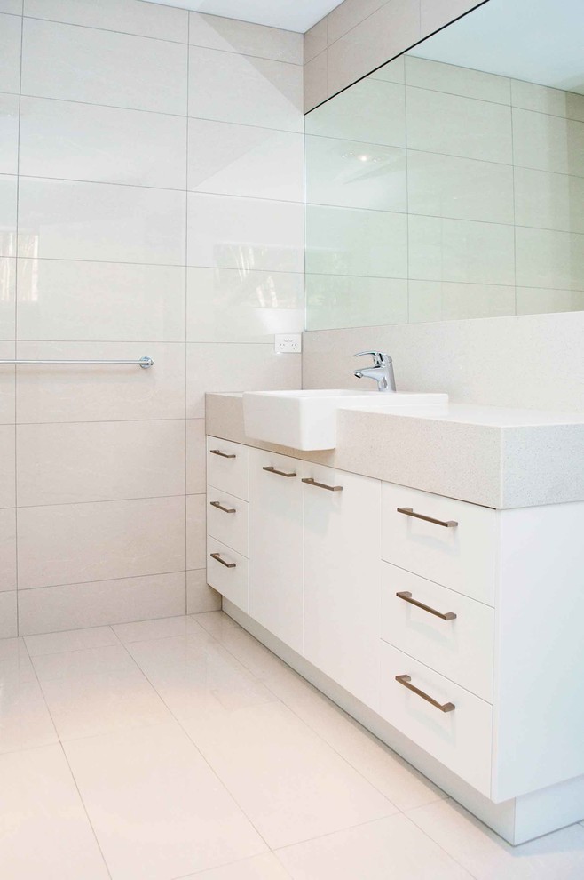 This is an example of a small modern ensuite bathroom in Sunshine Coast with a built-in sink, flat-panel cabinets, white cabinets, engineered stone worktops, white tiles, porcelain tiles, white walls and porcelain flooring.