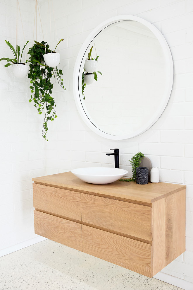 Modern inredning av ett badrum, med vit kakel, vita väggar, ett konsol handfat och träbänkskiva