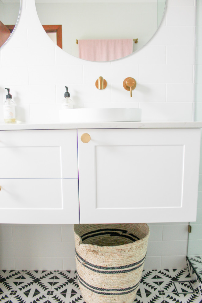 На фото: главная ванная комната среднего размера в современном стиле с фасадами в стиле шейкер, белыми фасадами, угловым душем, унитазом-моноблоком, белой плиткой, керамической плиткой, белыми стенами, полом из мозаичной плитки, настольной раковиной, столешницей из искусственного кварца, разноцветным полом, душем с распашными дверями, белой столешницей, сиденьем для душа, тумбой под две раковины и подвесной тумбой