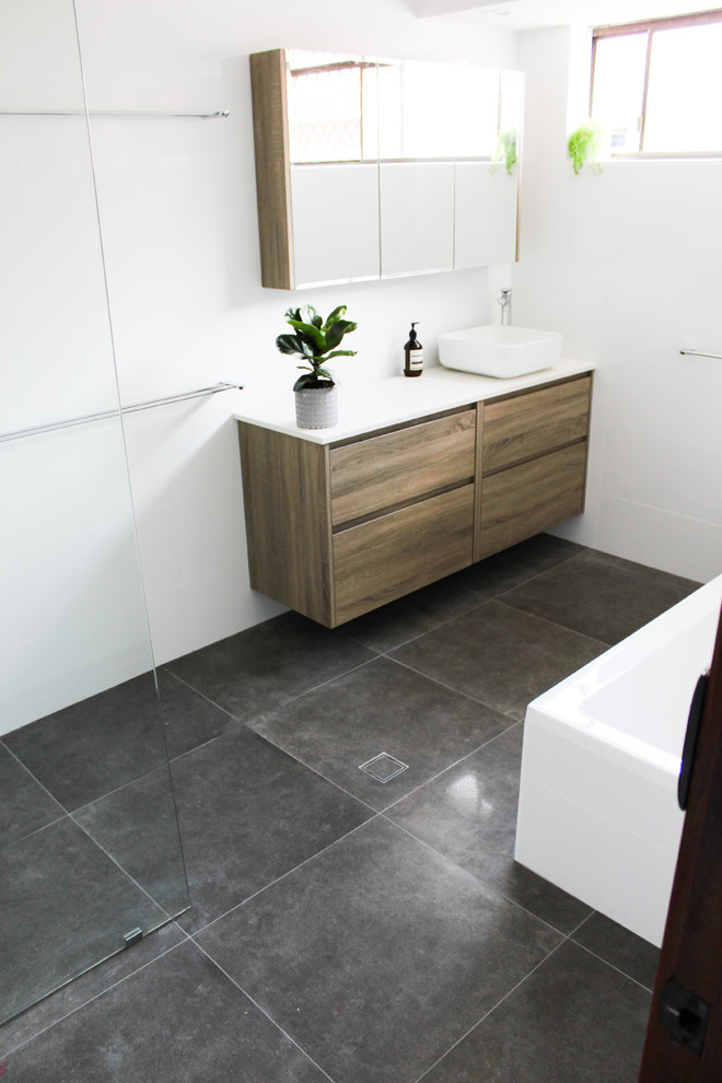 This is an example of a large family bathroom in Perth with flat-panel cabinets, brown cabinets, a built-in bath, a walk-in shower, white tiles, ceramic tiles, white walls, porcelain flooring, a vessel sink, engineered stone worktops, grey floors, an open shower and white worktops.
