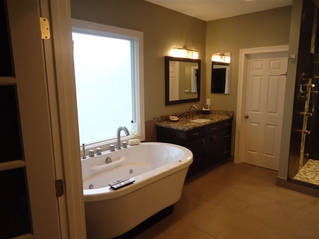 Inspiration for a large modern master beige tile and ceramic tile ceramic tile bathroom remodel in Indianapolis with an undermount sink, flat-panel cabinets, dark wood cabinets, granite countertops and green walls