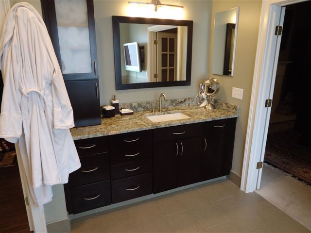 Photo of a modern ensuite bathroom in Indianapolis with a submerged sink, flat-panel cabinets, dark wood cabinets, granite worktops, beige tiles, ceramic tiles, beige walls and ceramic flooring.