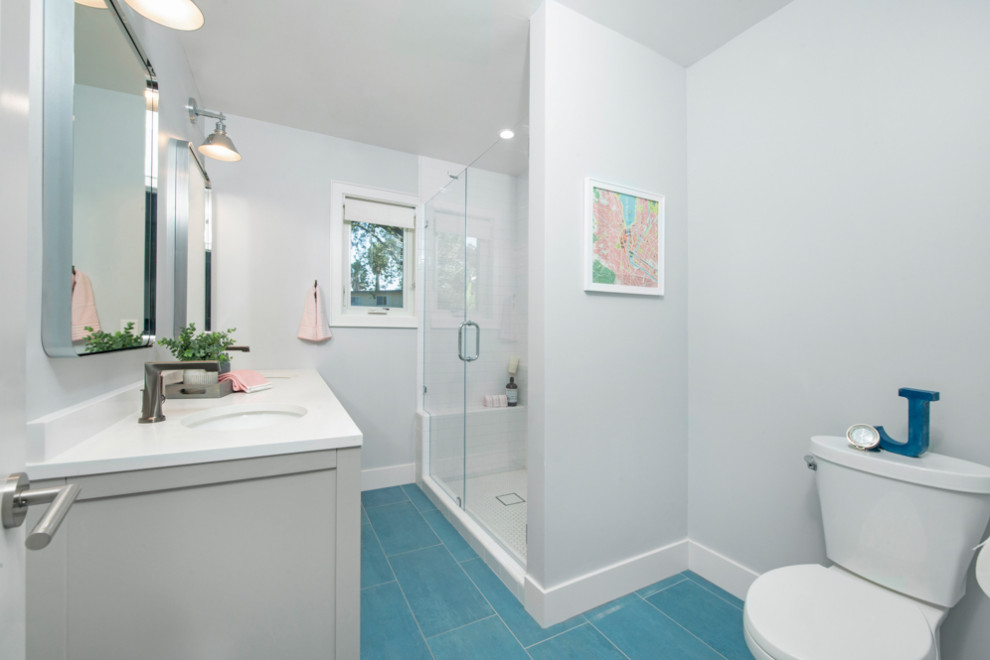 Klassisk inredning av ett mellanstort vit vitt badrum för barn, med släta luckor, grå skåp, en dusch i en alkov, en toalettstol med hel cisternkåpa, vit kakel, keramikplattor, grå väggar, klinkergolv i porslin, ett undermonterad handfat, bänkskiva i kvarts, blått golv och dusch med gångjärnsdörr