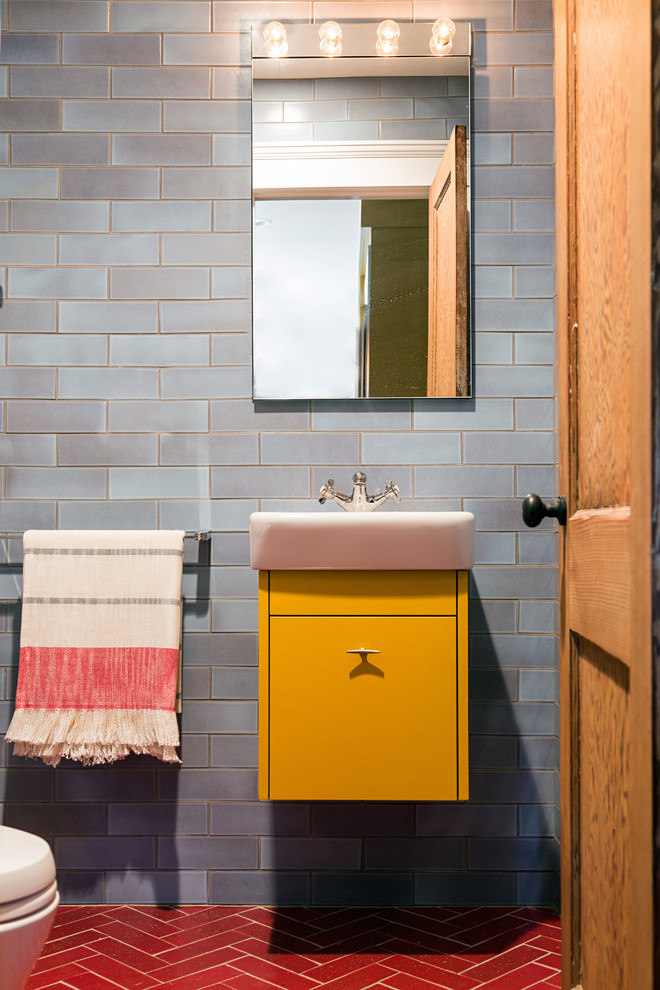 Exempel på ett modernt badrum, med släta luckor, gula skåp, blå kakel, keramikplattor, blå väggar, klinkergolv i keramik och ett väggmonterat handfat