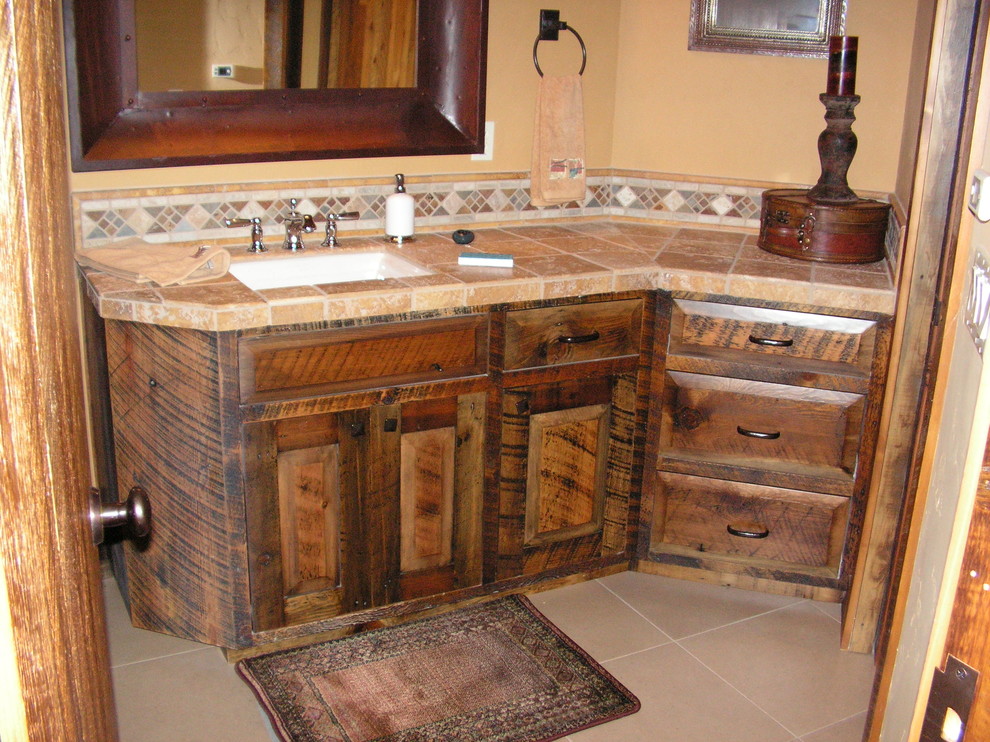 Inredning av ett rustikt mellanstort badrum med dusch, med ett undermonterad handfat, möbel-liknande, skåp i slitet trä, kaklad bänkskiva, en toalettstol med hel cisternkåpa, brun kakel, keramikplattor, bruna väggar och travertin golv