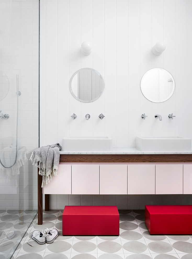 Modelo de cuarto de baño nórdico con armarios con paneles lisos, ducha esquinera, baldosas y/o azulejos blancos, baldosas y/o azulejos de cemento, paredes blancas, lavabo sobreencimera, suelo gris y encimeras grises