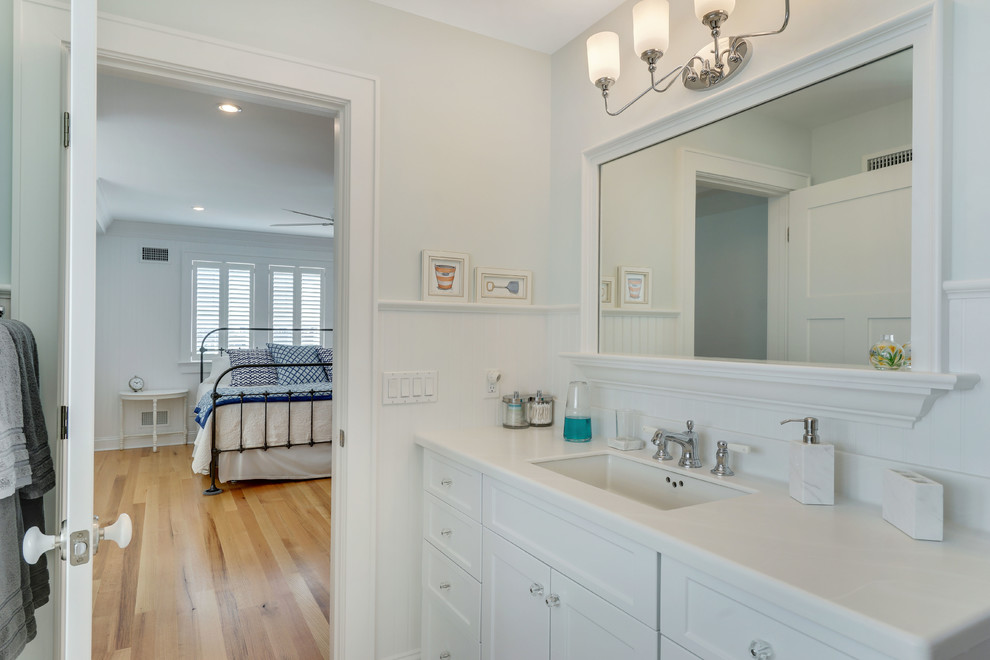 На фото: ванная комната в морском стиле с фасадами с утопленной филенкой, белыми фасадами, белой плиткой, плиткой кабанчик, синими стенами, мраморным полом и врезной раковиной с