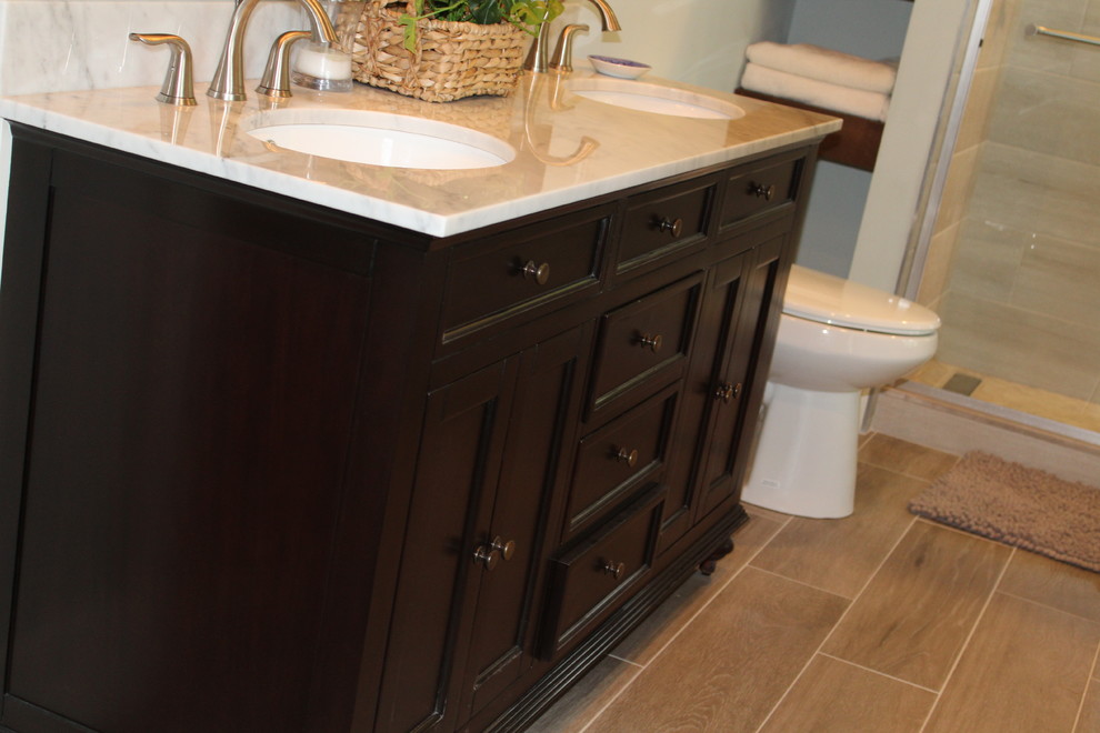 Design ideas for a large traditional ensuite bathroom in Atlanta with freestanding cabinets, dark wood cabinets, an alcove shower, a two-piece toilet, beige tiles, travertine tiles, grey walls, ceramic flooring, a submerged sink, granite worktops, brown floors, a sliding door and grey worktops.