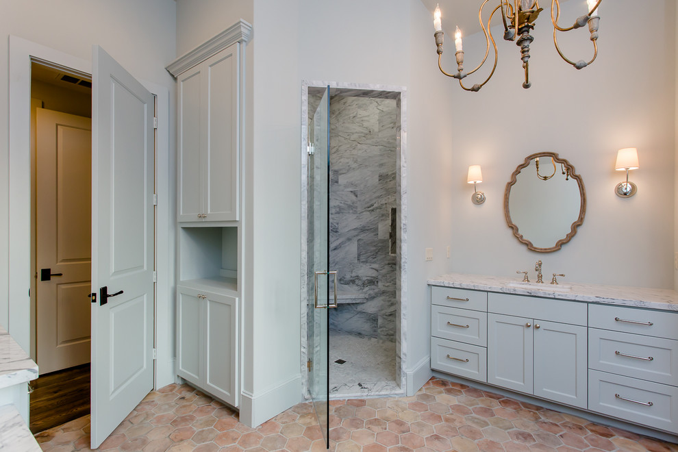 Idéer för ett mellanstort klassiskt en-suite badrum, med luckor med infälld panel, blå skåp, en hörndusch, en toalettstol med separat cisternkåpa, grå kakel, stenkakel, beige väggar, klinkergolv i terrakotta, ett undermonterad handfat och marmorbänkskiva