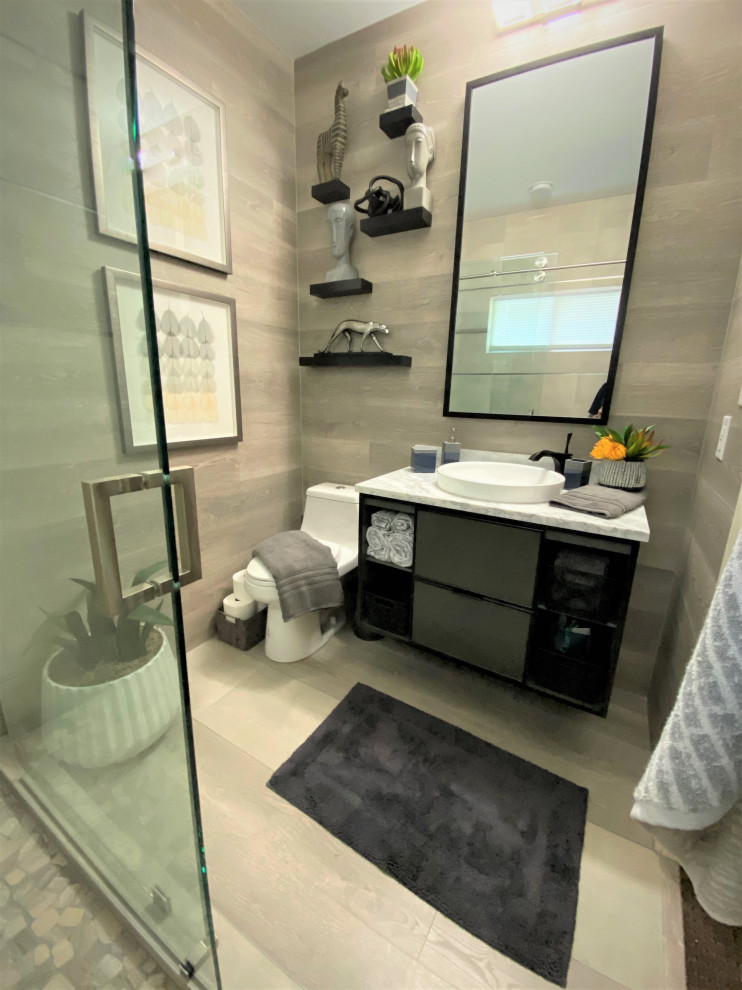 Idéer för att renovera ett mellanstort funkis grå grått badrum med dusch, med en dubbeldusch, keramikplattor, ett fristående handfat, dusch med skjutdörr, släta luckor, svarta skåp, grå kakel, ljust trägolv, granitbänkskiva och beiget golv