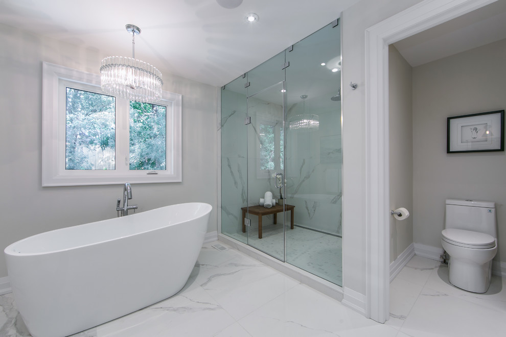 На фото: большая главная ванная комната в современном стиле с плоскими фасадами, белыми фасадами, отдельно стоящей ванной, двойным душем, унитазом-моноблоком, белой плиткой, мраморной плиткой, серыми стенами, полом из керамогранита, накладной раковиной, мраморной столешницей, белым полом, душем с распашными дверями и белой столешницей
