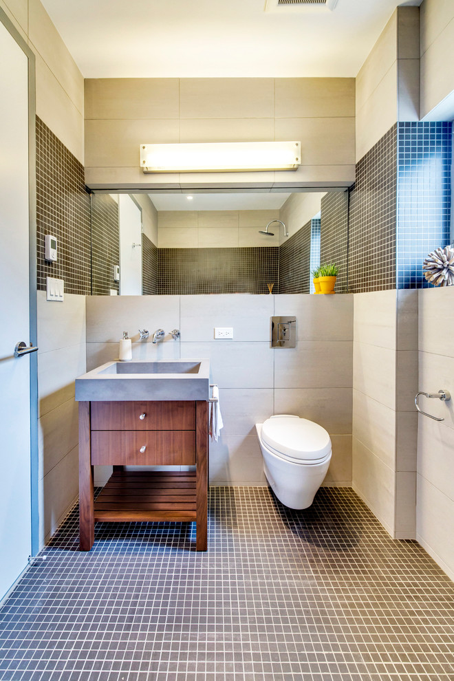 Idee per una stanza da bagno contemporanea di medie dimensioni con lavabo integrato, ante in legno bruno, top in cemento, WC sospeso, piastrelle grigie, piastrelle in gres porcellanato, pavimento con piastrelle a mosaico e ante lisce