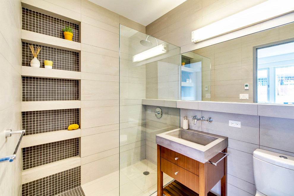 Inredning av ett modernt mellanstort en-suite badrum, med ett integrerad handfat, skåp i mörkt trä, bänkskiva i betong, en dusch i en alkov, en toalettstol med separat cisternkåpa, grå kakel, porslinskakel och släta luckor