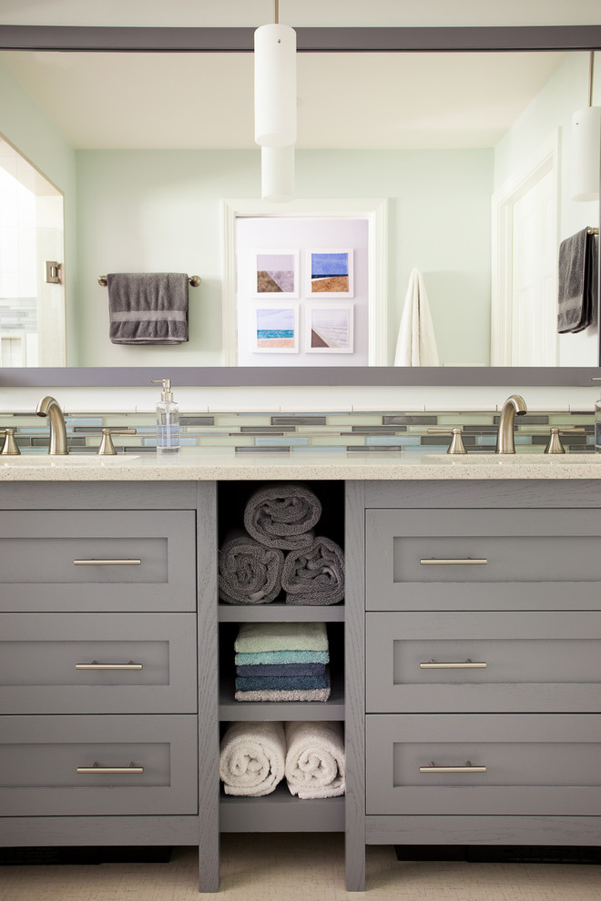 Пример оригинального дизайна: главная ванная комната среднего размера в стиле неоклассика (современная классика) с серыми фасадами, разноцветной плиткой, врезной раковиной, плоскими фасадами, двойным душем, плиткой из листового стекла, полом из галечной плитки, столешницей из искусственного кварца, белой столешницей и душем с распашными дверями
