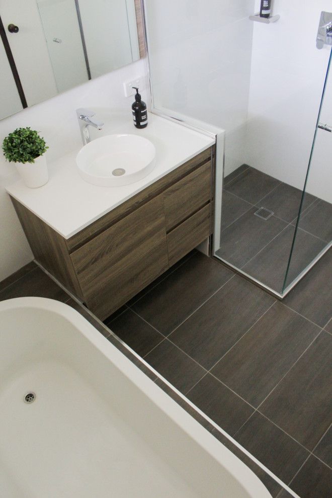 Photo of a small modern family bathroom in Perth with flat-panel cabinets, dark wood cabinets, a built-in bath, a corner shower, white tiles, ceramic tiles, white walls, porcelain flooring, a vessel sink, engineered stone worktops, brown floors, a hinged door and white worktops.