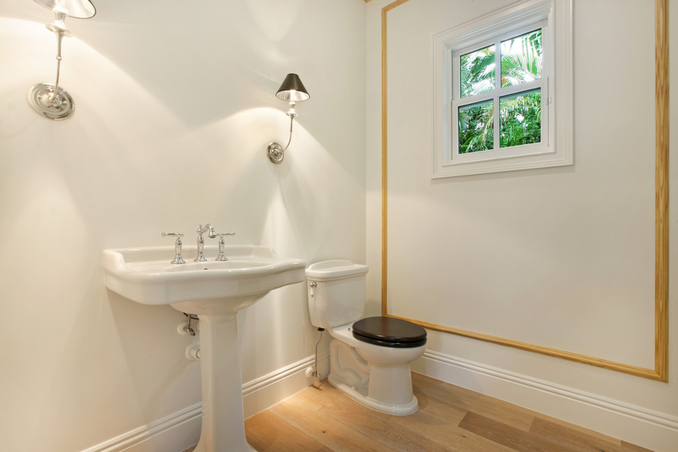 Diseño de cuarto de baño costero pequeño con sanitario de una pieza, paredes blancas, suelo de madera clara y aseo y ducha
