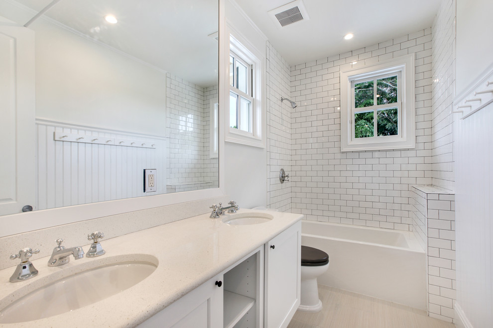 Exempel på ett litet maritimt en-suite badrum, med vita skåp, ett hörnbadkar, en hörndusch, en toalettstol med hel cisternkåpa, vit kakel, tunnelbanekakel, vita väggar, marmorgolv, ett undermonterad handfat och bänkskiva i kvarts