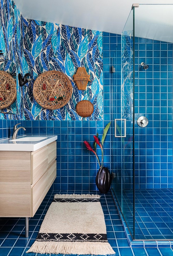Пример оригинального дизайна: маленькая ванная комната в стиле фьюжн с плоскими фасадами, светлыми деревянными фасадами, синей плиткой, керамической плиткой, разноцветными стенами, монолитной раковиной, душевой кабиной и столешницей из искусственного камня для на участке и в саду