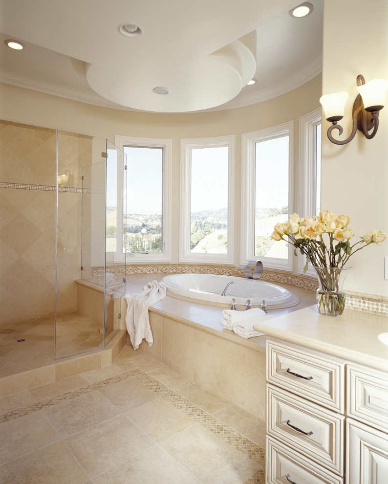 Стильный дизайн: большая главная ванная комната с белыми фасадами, мраморной столешницей, гидромассажной ванной, бежевой плиткой, каменной плиткой, бежевыми стенами и мраморным полом - последний тренд