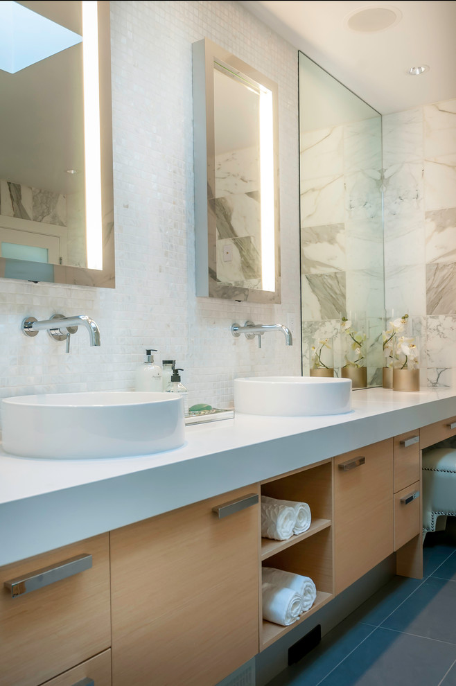 Medium sized contemporary ensuite bathroom in Vancouver with flat-panel cabinets, light wood cabinets, a freestanding bath, a corner shower, a one-piece toilet, white tiles, white walls, a vessel sink, solid surface worktops, marble tiles, porcelain flooring and grey floors.