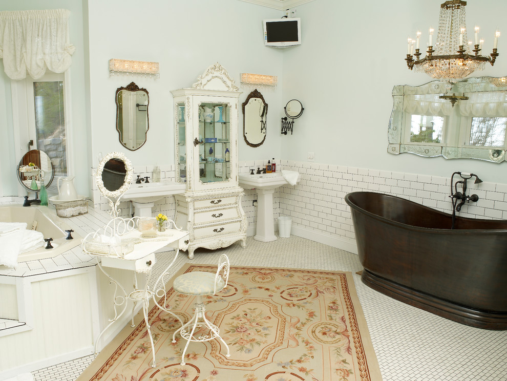 シャーロットにある高級な広いシャビーシック調のおしゃれなマスターバスルーム (置き型浴槽、ペデスタルシンク、白いキャビネット、白いタイル、セラミックタイル、青い壁、磁器タイルの床、落し込みパネル扉のキャビネット) の写真