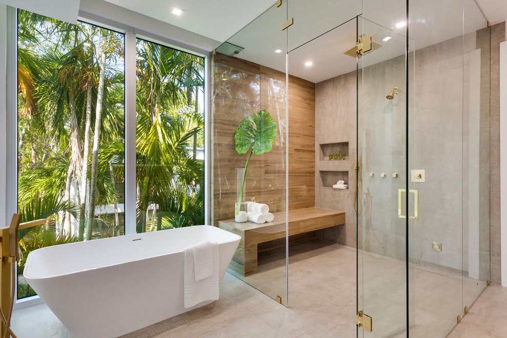 This is an example of a contemporary bathroom in Miami with a freestanding bath, a built-in shower, grey tiles, grey walls, concrete flooring, grey floors, a hinged door, a wall niche and a shower bench.