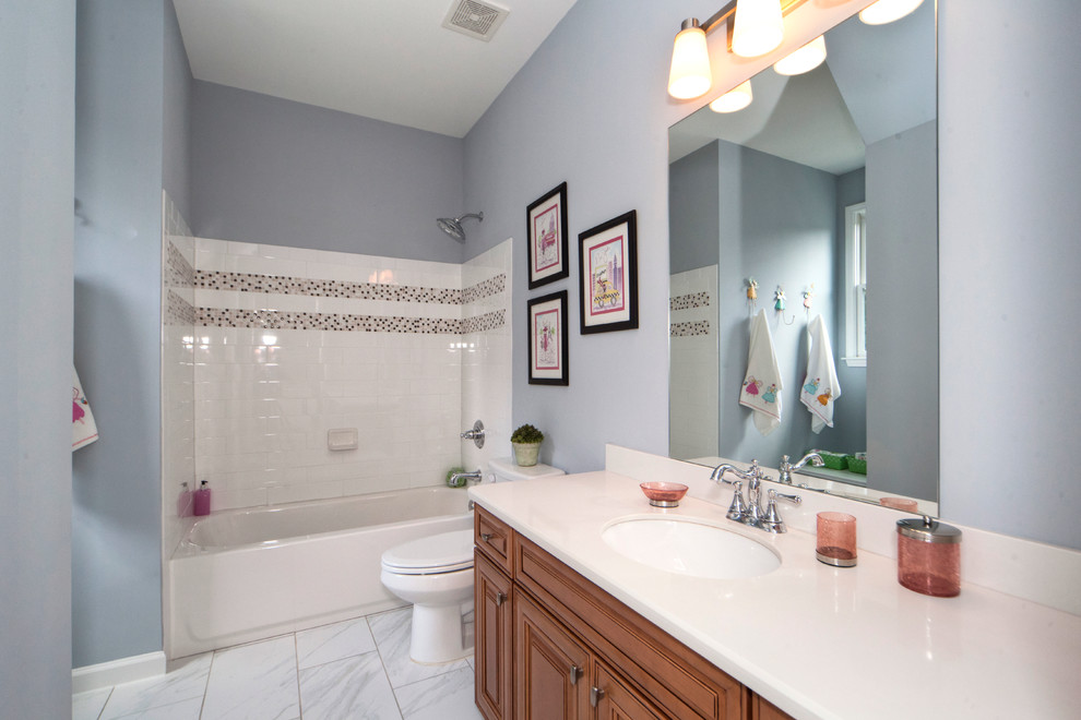 Exempel på ett mellanstort klassiskt badrum för barn, med ett undermonterad handfat, luckor med upphöjd panel, skåp i mellenmörkt trä, marmorbänkskiva, ett platsbyggt badkar, en dusch/badkar-kombination, en toalettstol med hel cisternkåpa, vit kakel, keramikplattor, blå väggar och klinkergolv i keramik
