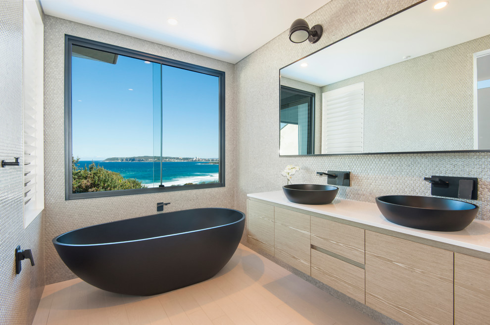 Design ideas for a contemporary bathroom in Sydney with a vessel sink, flat-panel cabinets, light wood cabinets, a freestanding bath, grey tiles and mosaic tiles.