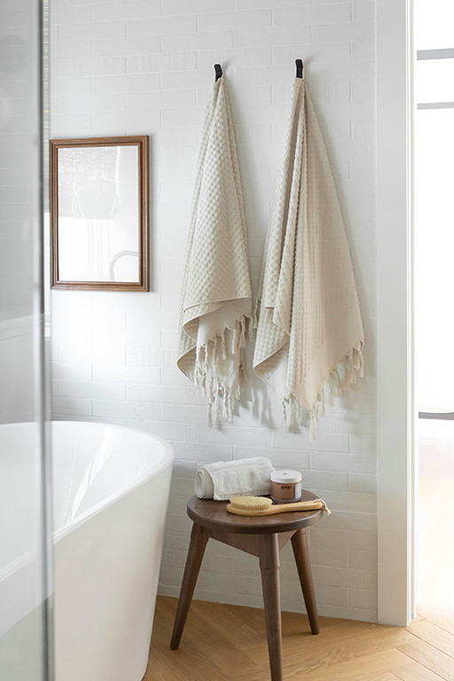 Inspiration för ett mellanstort funkis vit vitt en-suite badrum, med skåp i shakerstil, vita skåp, ett fristående badkar, en hörndusch, vit kakel, vita väggar, ljust trägolv, brunt golv och dusch med gångjärnsdörr