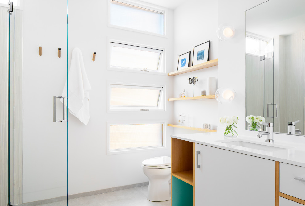 На фото: ванная комната среднего размера в стиле модернизм с плоскими фасадами, белыми фасадами, душем в нише, унитазом-моноблоком, серой плиткой, цементной плиткой, белыми стенами, бетонным полом, душевой кабиной, консольной раковиной, столешницей из кварцита, серым полом, душем с распашными дверями и белой столешницей с