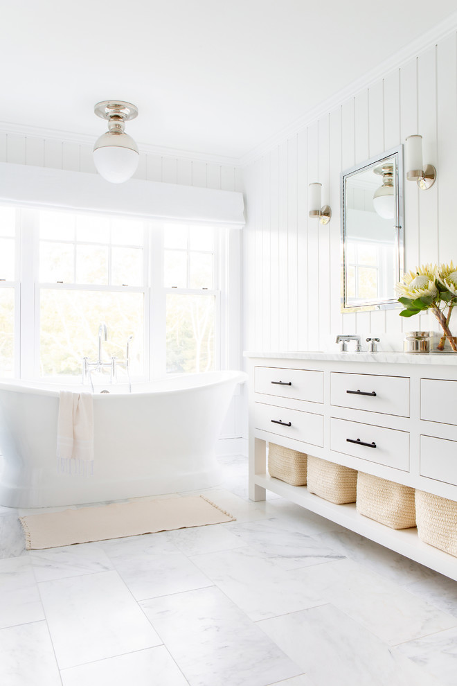 Пример оригинального дизайна: главная ванная комната среднего размера в морском стиле с белыми фасадами, отдельно стоящей ванной, белыми стенами, врезной раковиной, белым полом, белой столешницей, унитазом-моноблоком, мраморным полом, мраморной столешницей и плоскими фасадами